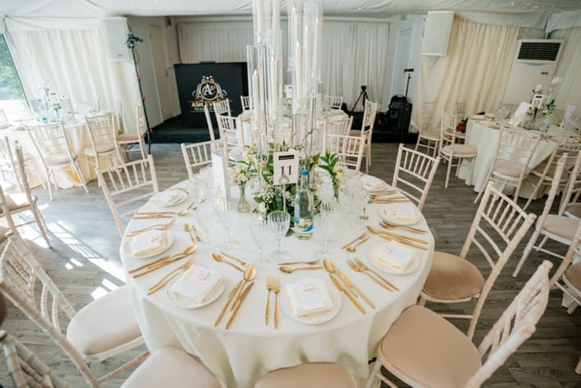 Round wedding table setup with Chiavari chairs and premium place settings